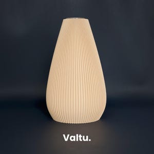 Puede incluir: Una pantalla de lámpara plisada beige con forma de lágrima redondeada. La pantalla está hecha de un material suave y texturizado con un brillo sutil.