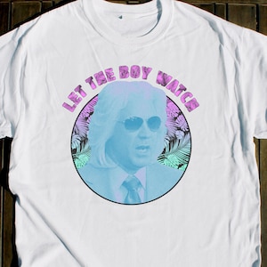 Pode incluir: Camiseta branca com um gráfico azul e rosa de um homem usando óculos de sol e um terno. O gráfico diz "Let the boy watch".