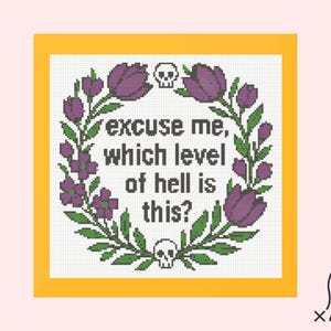 Puede incluir: Diseño de punto de cruz con borde amarillo, con una corona floral en verde y morado. El texto dice "perdón, ¿en qué nivel del infierno estamos?" con acentos de calavera. El diseño está sobre un fondo blanco.