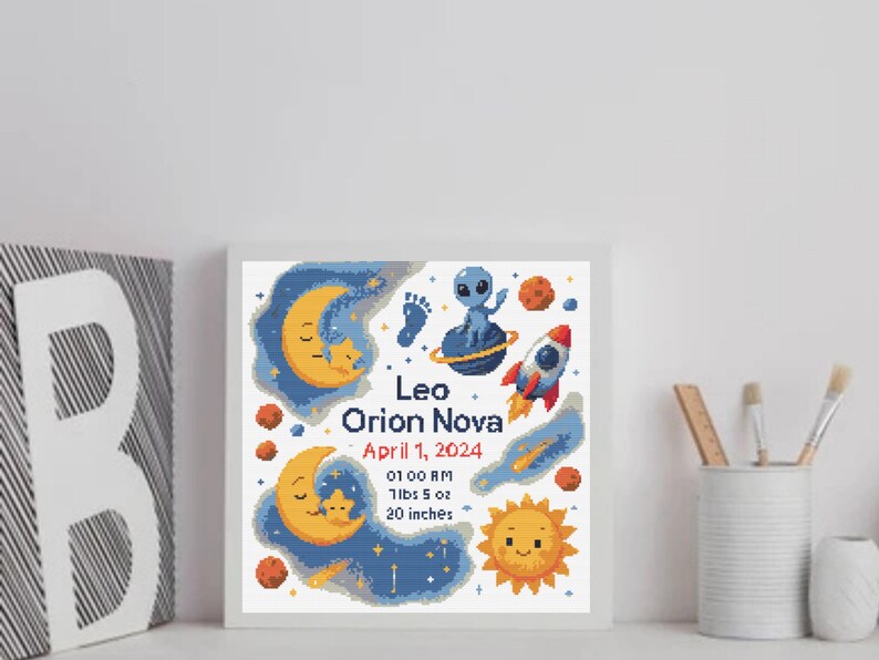 May include: A framed, cross-stitch style artwork featuring a space theme. The design includes a crescent moon, stars, a rocket, an alien, and the text "Leo Orion Nova, April 1, 2024, 7lbs 5 oz, 20 inches". The color palette includes blue, orange, and yellow.
