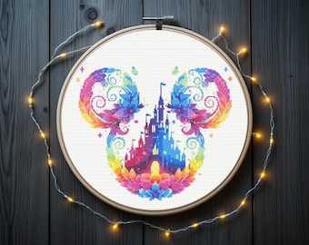 May include: A colorful cross-stitch design featuring a castle in the center, surrounded by a Mickey Mouse head shape. The design uses a rainbow of colors, including pink, yellow, blue, and purple. The cross-stitch is set in a wooden embroidery hoop.