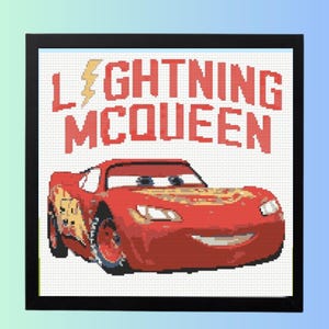 May include: A framed cross-stitch featuring Lightning McQueen from the Cars movie. The red race car is smiling below the words "LIGHTNING MCQUEEN" in red block letters with a yellow lightning bolt. The artwork is framed in black.