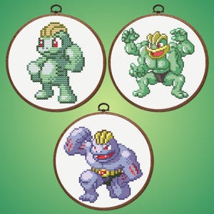 Puede incluir: Tres aros de bordado de punto de cruz con personajes de Pokémon. Los personajes son en tonos verdes y morados, con detalles en rojo y amarillo. Cada aro es redondo con un marco de madera y un lazo metálico para colgar.