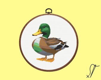 Puede incluir: Un aro de bordado de punto de cruz con una imagen colorida de un pato silvestre. El pato es marrón, verde y blanco con un pico amarillo.