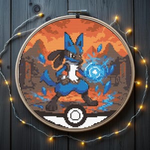 Könnte beinhalten: Kreuzstich-Stickerei eines blau-schwarzen Lucario-Charakters, der eine blaue Energiesphäre hält, vor dem Hintergrund eines himmel- und bergfarbenen Sonnenuntergangs. Das Design ist in einem Holzreifen gerahmt, mit einem Pokeball am unteren Rand.