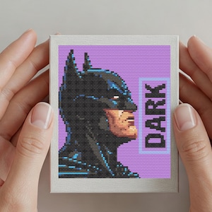 Puede incluir: Imagen pixelada de Batman de perfil, sobre un fondo morado. La palabra "DARK" se muestra verticalmente en un rectángulo azul. La obra de arte se presenta en un formato pequeño y cuadrado.