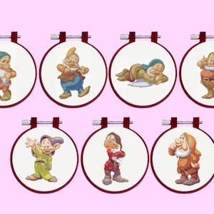 May include: Seven circular embroidery hoops with dark red frames, each containing a white fabric panel featuring a cross-stitched character. The characters are depicted in various poses, wearing colorful tunics, hats, and belts in shades of blue, green, red, and brown.