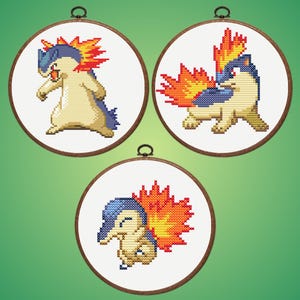 May include: Three circular cross-stitch hoops displaying a cartoon character with flames. The character is in different poses, using beige, blue, orange, and yellow. The hoops have a wooden frame and a metal hanging loop.