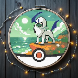 Op de afbeelding: Een kruissteekborduurwerk met een gepixeld wezen in wit en grijs met blauwe accenten, tegen een kustlandschap. Het kunstwerk wordt getoond in een houten borduurring, met lichtslingers eromheen.