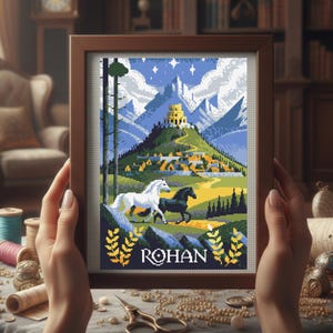 May include: A framed cross-stitch depicting a landscape with a castle, mountains, and two horses. The artwork features a white and a black horse running across a green field. The word "ROHAN" is at the bottom.
