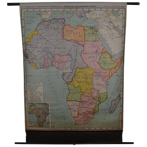 May include: Vintage map of Africa, featuring detailed geographical information and country borders. The map is printed on a large sheet, with a dark wooden rod at the top and bottom for hanging. The title "American Geographers Series" is visible.