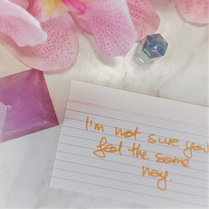 May include: A white index card with lined paper and the handwritten message "I'm not sure you feel the same way."