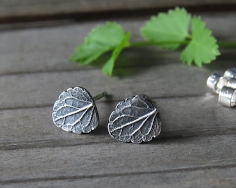 Puede incluir: Un par de pendientes de plata con forma de hoja. Los pendientes están hechos de metal y tienen un diseño de hoja detallado.