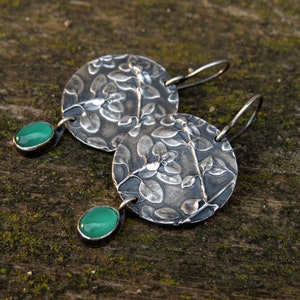 Puede incluir: Pendientes de plata con dise&ntilde;o floral y detalles de piedras preciosas verdes.