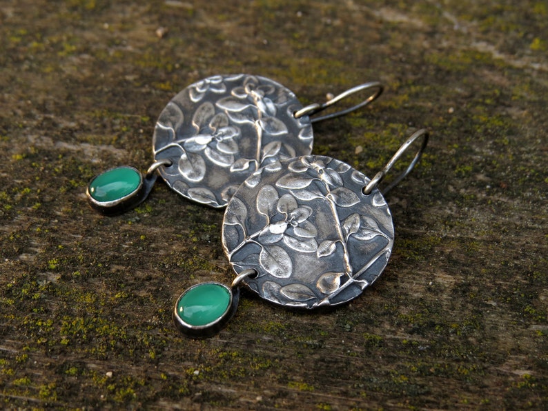Puede incluir: Pendientes de plata con dise&ntilde;o floral y detalles de piedras preciosas verdes.