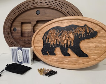 以下が含まれることがあります： クマのデザインの木製クリベッジボードセット、トランプ、ペグ。クマのデザインは木に彫られ、黒い染料で満たされています。セットには、黒いベルベットのバッグと濃い茶色の楕円形のクリベッジボードが含まれています。