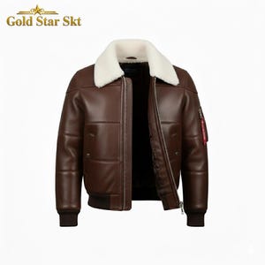 Puede incluir: Chaqueta bomber de cuero marrón con cuello de borrego blanco. La chaqueta tiene cremallera, múltiples bolsillos y una etiqueta roja en la manga. El texto "Gold Star Skt" está en la parte superior izquierda. Una prenda de abrigo clásica.