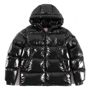 Op de afbeelding: Een glanzende zwarte pufferjas met capuchon. De jas heeft een glanzend, gewatteerd uiterlijk en een ritssluiting over de hele lengte. Hij heeft twee zijzakken en een kleine zak op de linkermouw. Deze winterjas is ontworpen voor warmte en stijl.