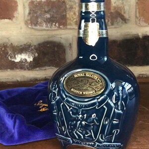 May include: A blue ceramic bottle of Royal Salute Scotch Whisky with a gold label and a silver cap. The bottle is decorated with a crest and the words "Chivas Brothers Ltd."
