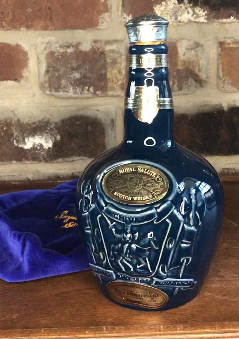 May include: A blue ceramic bottle of Royal Salute Scotch Whisky with a gold label and a silver cap. The bottle is decorated with a crest and the words "Chivas Brothers Ltd."