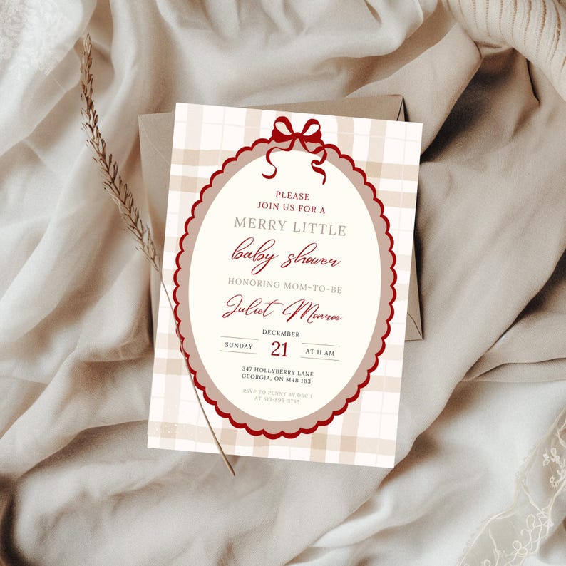 May include: A baby shower invitation with a plaid background and a decorative oval frame. The invitation text is in burgundy and includes the words "Merry Little baby shower" and the name "Juliet Monroe". The date is December 21st.