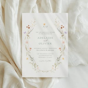 May include: A wedding invitation with floral detailing. The invitation includes the names "Adelaide and Olivier" and event information. The text is surrounded by a delicate floral border with pastel flowers and greenery. The background is a soft, off-white colour.