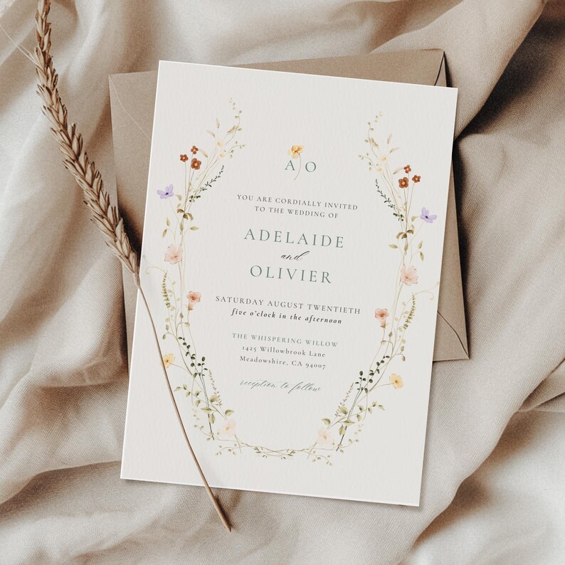 May include: A wedding invitation with floral detailing. The invitation includes the names "Adelaide and Olivier" and event information. The design features a floral border with colorful flowers and foliage. The invitation is on cream paper with a matching envelope.