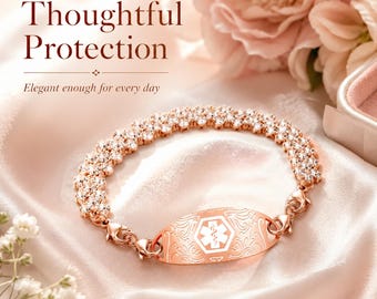 May include: A rose gold medical alert bracelet featuring a central oval plate with an engraved floral pattern and a white medical caduceus symbol, connected to a sparkling multi-row cubic zirconia chain with lobster claw clasps.
