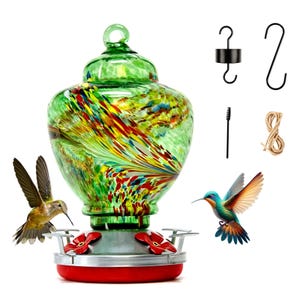 May include: A glass hummingbird feeder with a green, yellow, and red speckled pattern, featuring a silver base with red flower-shaped feeding ports. Includes a black metal hook, an S-hook, a small cleaning brush, and a length of twine.