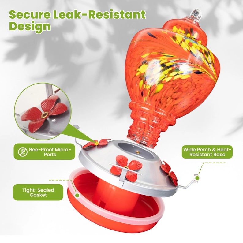 May include: A hummingbird feeder with a vibrant orange and yellow swirled glass reservoir, a silver metal lid, and a red base. It features red flower-shaped feeding ports, a tight-sealed gasket, and a wide perch. Text includes Secure Leak-Resistant Design.