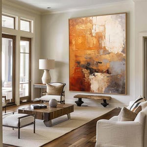 Può includere: Grande dipinto astratto con superficie materica, nei toni dell'arancione, bianco, grigio e nero. L'opera incorniciata è appesa in un soggiorno luminoso con mobili in legno, un tappeto e una palette di colori neutri.