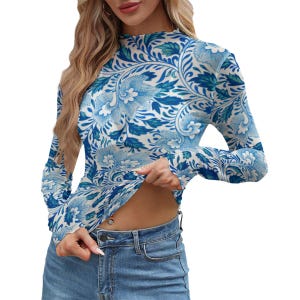 May include: A long-sleeved top with a blue and white floral design. The top has a high neckline and a fitted shape. The floral pattern includes stylized flowers and leaves. The material looks lightweight, suitable for layering. The top is a stylish garment.