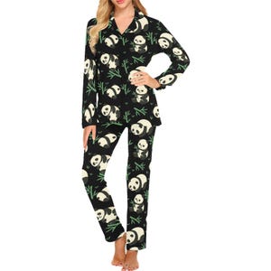 Puede incluir: Conjunto de pijama negro con estampado de panda. La parte superior de manga larga y los pantalones presentan ilustraciones de pandas blancos y negros con tallos de bamb&uacute;. El pijama tiene cuello y cierre de botones.