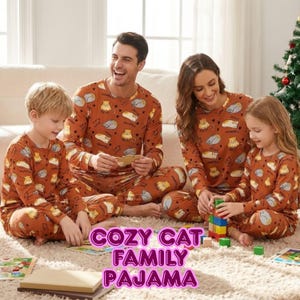 Op de afbeelding: Bijpassende familiepyjamasets in een roestkleur, met een herhaald patroon van cartoonkatten. De tops en broeken met lange mouwen worden gedragen door een gezin van vier. De tekst "COZY CAT FAMILY PAJAMA" wordt in een roze lettertype weergegeven.