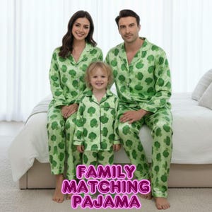 Könnte beinhalten: Passende Familien-Pyjama-Sets in hellgrüner Farbe mit Brokkoli-Muster. Die Sets beinhalten ein Hemd mit Knöpfen und eine Hose. Das Bild zeigt eine dreiköpfige Familie, die die Pyjamas trägt. Der Text "FAMILY MATCHING PAJAMA" wird unten angezeigt.