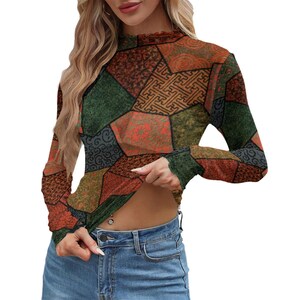 Könnte beinhalten: Ein langärmeliges Oberteil mit Stehkragen und einem mehrfarbigen Patchwork-Muster aus geometrischen Formen in Dunkelgrün, Rostorange und Braun, kombiniert mit einer blauen Jeans. Das Oberteil hat eine körpernahe Passform und eine strukturierte Optik.