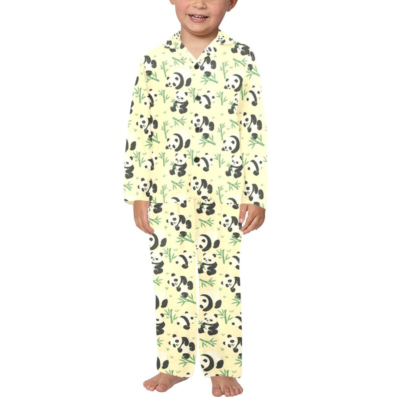 Puede incluir: Conjunto de pijama amarillo con un estampado repetido de pandas blancos y negros y tallos de bamb&uacute; verdes. La parte superior de manga larga tiene cuello y cierre de botones. Los pantalones a juego tienen un corte holgado.
