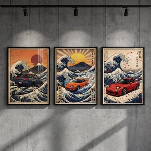 Puede incluir: Tres impresiones artísticas enmarcadas con diseños de inspiración japonesa que representan coches. Cada impresión muestra un coche corriendo a través de olas oceánicas con una montaña y un sol de fondo. Los coches son azules, naranjas y rojos.