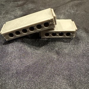 May include: Two gray concrete blocks with six holes each. The blocks are stacked on top of each other.