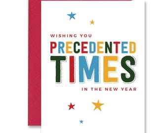 May include: A white greeting card with a red envelope. The card reads "Wishing you Precedented Times in the New Year" in colorful block letters. Small blue, red, and yellow stars are scattered around the text.