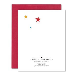 May include: A white greeting card with a red envelope. The card features a red star, a yellow star, and a blue star. The text "JONES STREET PRESS" is printed at the bottom, along with the design and copyright information.
