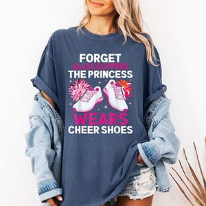 K&ouml;nnte beinhalten: Ein marineblaues T-Shirt mit einer Grafik von Cheerleader-Schuhen und dem Text "Forget glass slippers the princess wears cheer shoes".