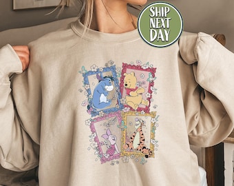 Può includere: Felpa color sabbia con una grafica colorata di Winnie the Pooh e amici in ritratti incorniciati. Il design include Eeyore, Pooh, Pimpi e Tigro, circondati da fiori e farfalle. La felpa ha maniche lunghe.