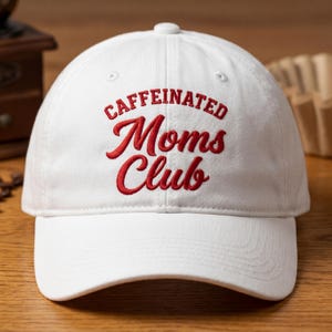 May include: A white ceramic mug with a black handle and the text "But First, Coffee" in a black, bold font. The mug is on a white surface. The mug is likely for hot beverages.