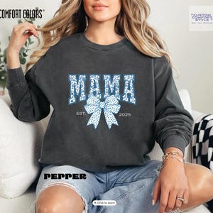 Elevate your style with this Custom Comfort Colors Mama Est Sweatshirt, a perfect blend of comfort and elegance. Designed with a Chinoiserie Blue Toile De Jouy pattern, this Coquette Bow Sweatshirt brings a timeless and feminine touch to any outfit. Whether you're looking for a girly aesthetic crewneck or a unique Mother's Day Gift, this Comfort Colors 1566 sweatshirt is a stylish and meaningful choice for moms.
Featuring a blue ribbon sweater design, this ribbon sweatshirt is inspired