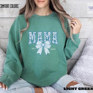 Elevate your style with this Custom Comfort Colors Mama Est Sweatshirt, a perfect blend of comfort and elegance. Designed with a Chinoiserie Blue Toile De Jouy pattern, this Coquette Bow Sweatshirt brings a timeless and feminine touch to any outfit. Whether you're looking for a girly aesthetic crewneck or a unique Mother's Day Gift, this Comfort Colors 1566 sweatshirt is a stylish and meaningful choice for moms.
Featuring a blue ribbon sweater design, this ribbon sweatshirt is inspired