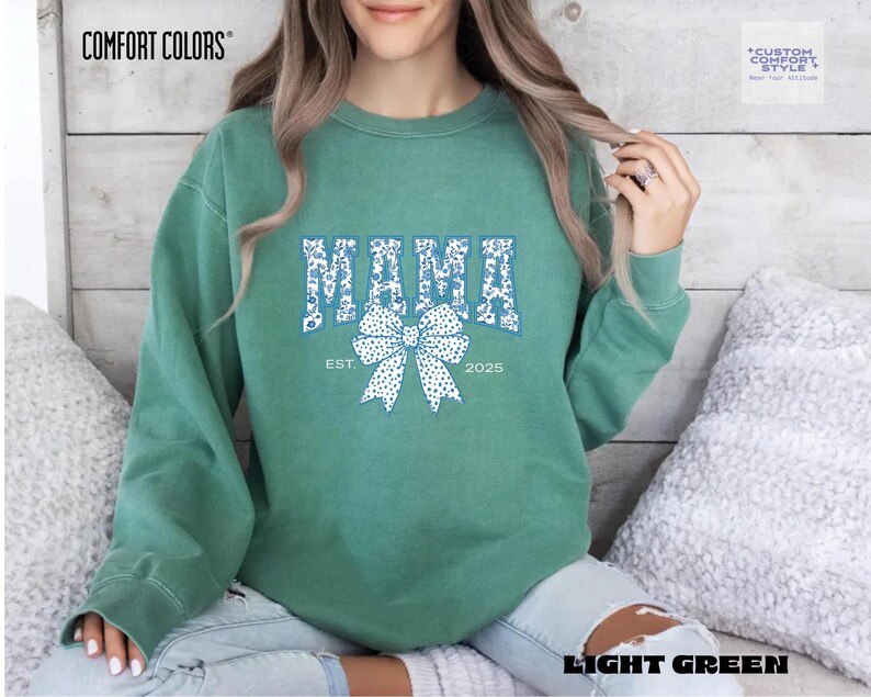 Elevate your style with this Custom Comfort Colors Mama Est Sweatshirt, a perfect blend of comfort and elegance. Designed with a Chinoiserie Blue Toile De Jouy pattern, this Coquette Bow Sweatshirt brings a timeless and feminine touch to any outfit. Whether you're looking for a girly aesthetic crewneck or a unique Mother's Day Gift, this Comfort Colors 1566 sweatshirt is a stylish and meaningful choice for moms.
Featuring a blue ribbon sweater design, this ribbon sweatshirt is inspired