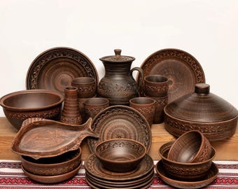 May include: A collection of handcrafted brown ceramic tableware, including plates, bowls, cups, a pitcher, and a serving dish. The pieces feature intricate carved designs and a rustic aesthetic, perfect for a warm, inviting dining experience.