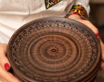 May include: A stack of brown ceramic plates with a decorative design around the rim. The plates are handmade and have a rustic look.