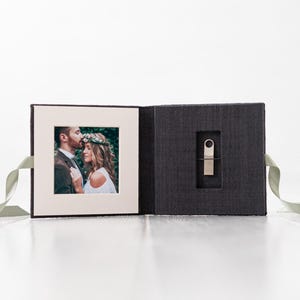 May include: A gray linen box with a ribbon closure. The box is open to reveal a photo of a couple and a silver USB drive.